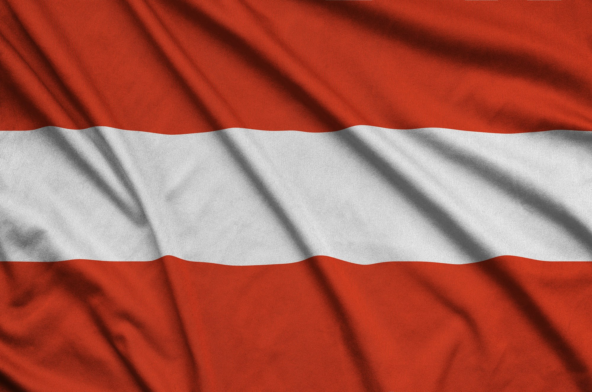 Austria flag is depicted on a sports cloth fabric with many folds. Sport team waving banner