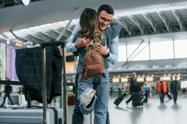 Embracing each other. Young couple is in the airport together