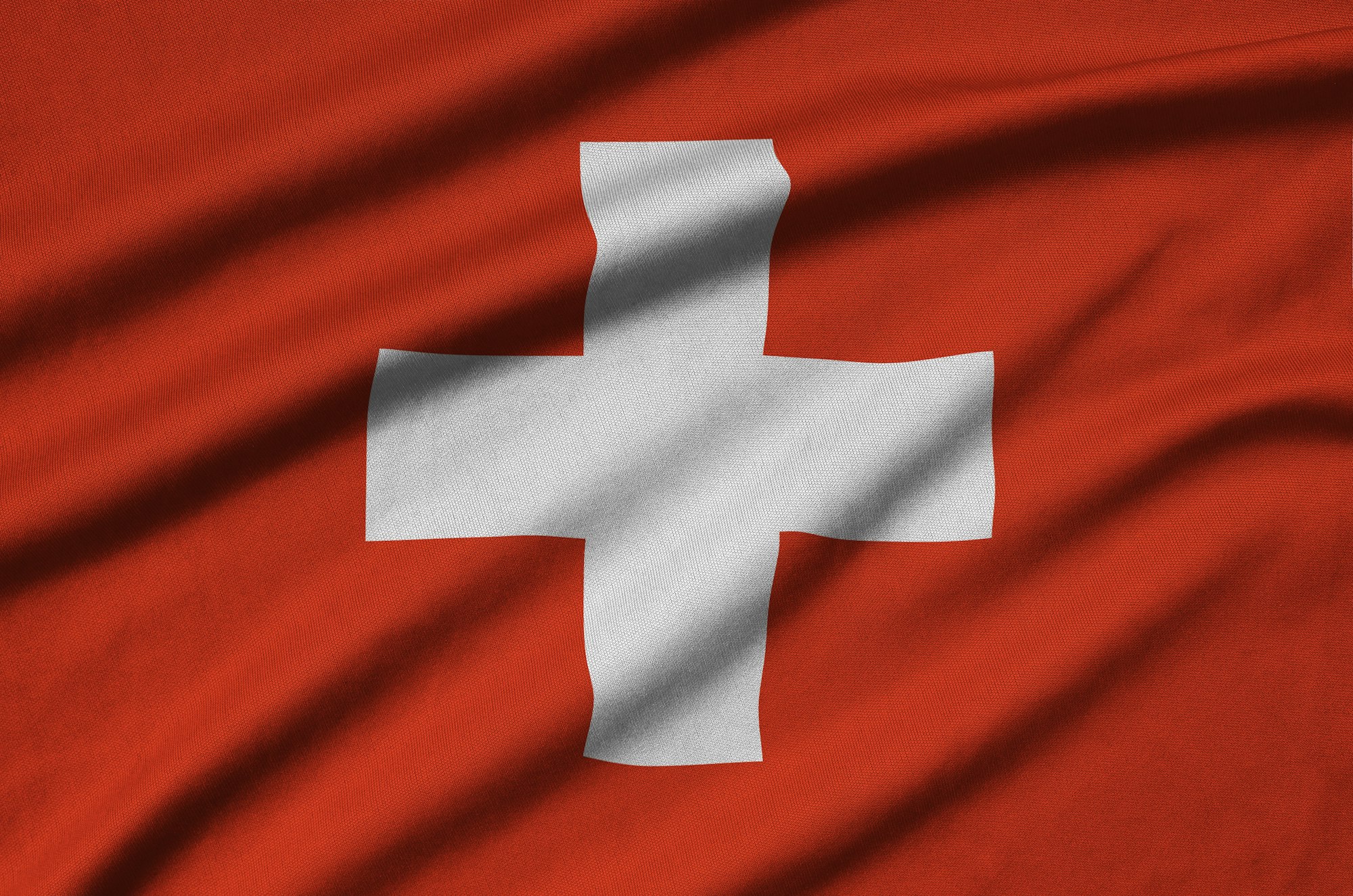 Switzerland flag is depicted on a sports cloth fabric with many folds. Sport team waving banner