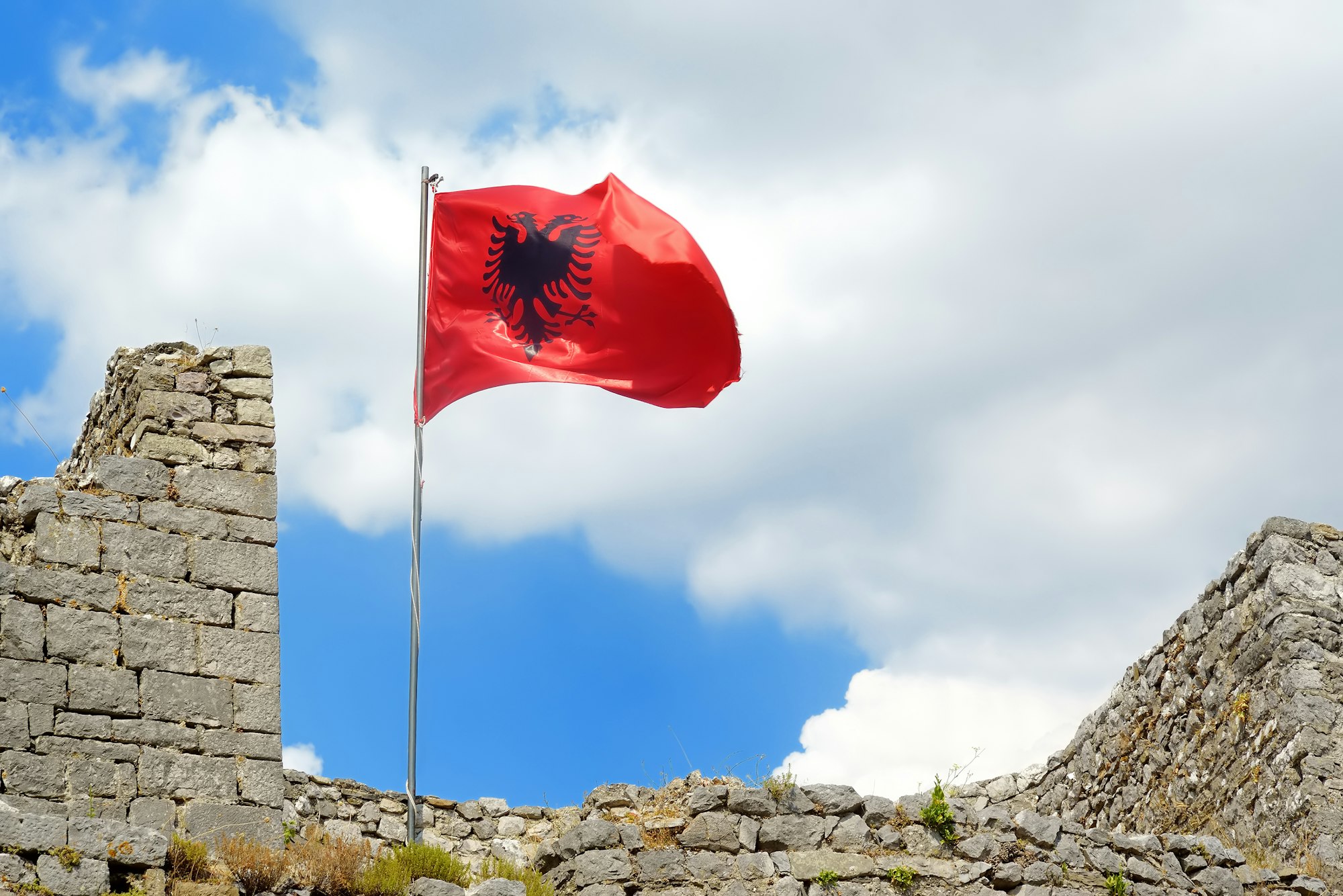 Red Albanian flag with black eagle waving over wall of Fortress Rozafa near Shkodra city